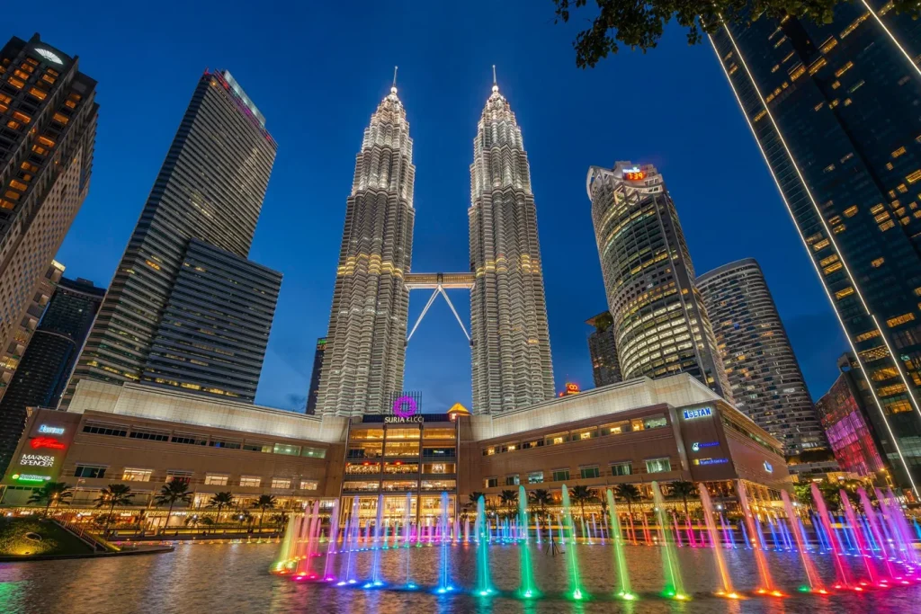 Suria KLCC and the PETRONAS Twin Towers seen across Lake Symphony at dusk
